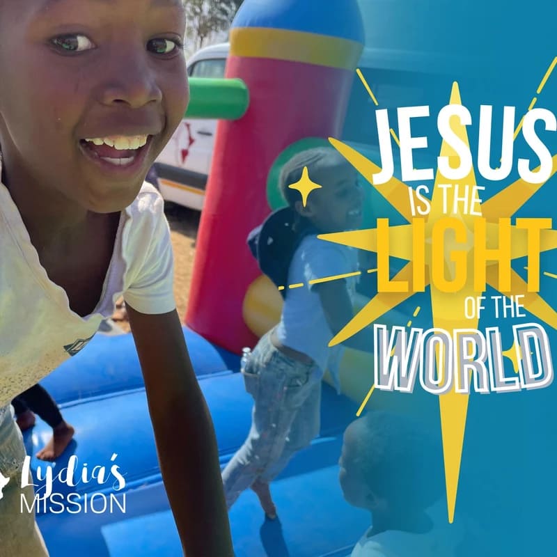 A happy young boy smiles at the camera while playing on a bounce house, with a graphic overlay that reads 'Jesus is the Light of the World'.